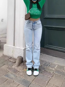 Women's light blue high-waisted wide-leg jeans styled with green crop top on urban street