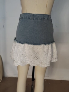 Gros plan d'une mini-jupe en jean avec patchwork de dentelle blanche et broderie florale