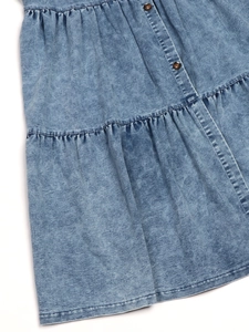 Detailed view of light blue denim dress showing tiered stitching and dark brown buttons