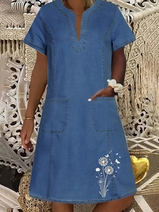Detail of blue denim dress with V-neck, square pockets and white dandelion flower prints