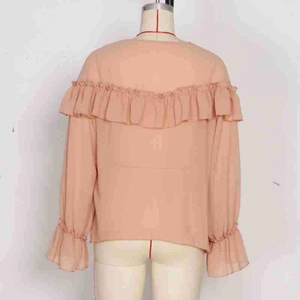 Detail of peach pink chiffon blouse featuring elegant ruffle layers and sheer back texture