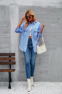 Detail of light blue denim shirt with frayed hem, chest pockets and button closure