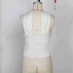 Close-up of white halter top showing vertical ruching detail and open back on a mannequin