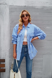 Close-up of distressed denim jacket featuring frayed hem and metallic buttons