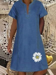 Dettaglio dell'abito in denim con scollo a V e stampa a margherita bianca su blu