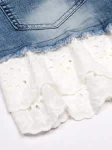 Vue détaillée de l'ourlet en jean effiloché avec délicat patchwork de dentelle blanche
