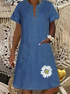 Detail of blue denim style V-neck dress with pockets and white daisy print on the hem