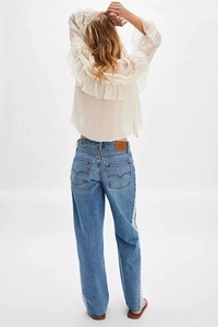 Macro detail of white chiffon blouse ruffles and blue denim jeans with classic red tab