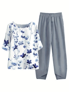 Detail of floral print top with unique crisscross hem on grey cotton linen trousers