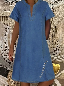 Dettaglio del ricamo di margherite bianche su abito a trapezio blu stile denim