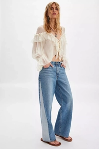 Detail of white chiffon blouse with ruffle layers and blue side-stitch wide-leg denim pants