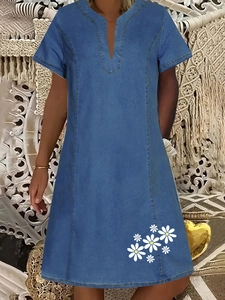 Dettaglio dell'abito in denim con scollo a V e stampa a margherite bianche sull'orlo inferiore