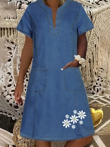 Detailed close-up of a blue V-neck dress featuring a white daisy print and functional pockets