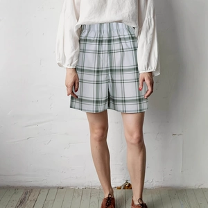 Detail of green plaid high-waist shorts featuring elastic waistband and cotton fabric