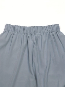 Detail view of the elastic waistband and fine pleated texture on floral print trousers