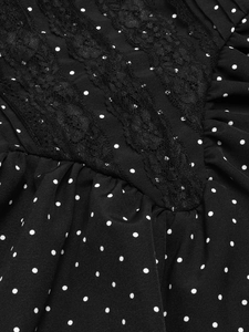 Detailed macro view of black polka dot fabric with intricate floral lace trim and pleats