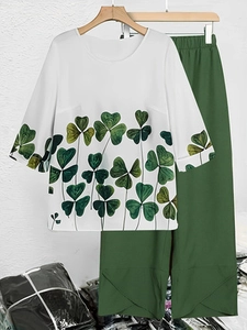 Detail of white round neck top with clover print and dark green wide leg trousers set