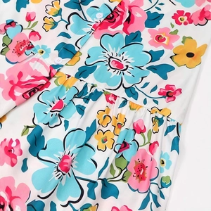 Detail of floral printed summer dress featuring colorful blossoms and white button closure