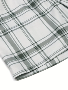 Close-up of green and white plaid fabric showing high-quality stitching on the hem line