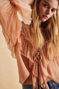 Close-up of elegant ruffles and delicate tie-neck detail on a sheer chiffon blouse