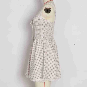 Detailed side view of white polka dot mini dress with elastic waist and lace trim hem