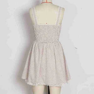 Detail of white polka dot dress featuring elastic pleated back and lace hem trim