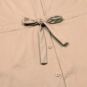 Detail of adjustable waist drawstring and matching buttons on a khaki safari style top