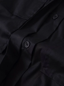 Dettaglio di una camicia nera in cotone con bottoni a quattro fori e trama del tessuto