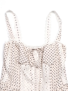Detail of polka dot camisole dress showing delicate white lace trim and front bow tie
