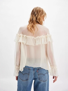 Elegant off-white chiffon blouse with ruffle trim and long sleeves, paired with denim jeans