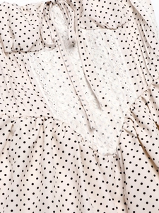 Detailed view of white polka dot dress featuring lace patchwork and delicate tie closure