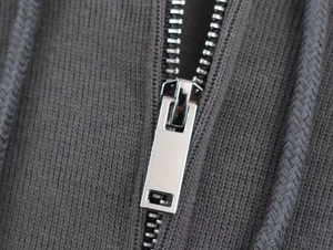 Macro shot of silver metal zipper and soft grey ribbed fabric texture on hoodie