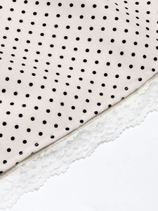 Close-up of pink polka dot fabric featuring exquisite white lace trim and stitching