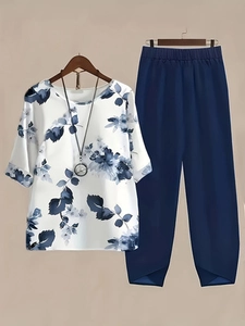 Detail of two-piece set featuring floral print top and navy pants with crossover hem design