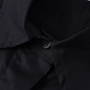 Dettaglio del colletto di una camicia nera stile utility con cuciture e bottone rifiniti