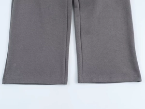 Detail view of smooth straight-leg dark gray cotton knit pants with clean rolled hem edge