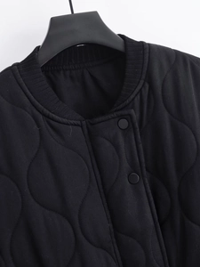 Detail of black quilted cotton jacket featuring ribbed collar and snap button closure