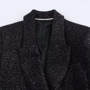 Detailed close-up of black tweed fabric with shimmering silver metallic threads and lapels