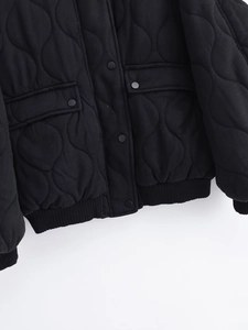 Detail of onion quilted pattern on black jacket with matte buttons and ribbed hem