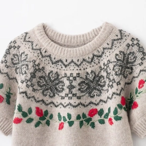 Detail of vintage beige knit sweater with Nordic jacquard and floral embroidery