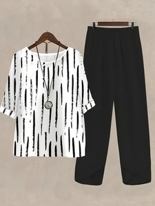 Detail of white floral print top with rolled cuffs and black split-hem wide-leg pants