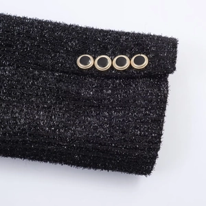 Close-up of black tweed fabric with silver glitter threads and golden buttons on sleeve