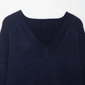 Detailed view of dark blue V-neck sweater showing fine knit texture and ribbed neckline