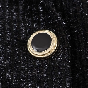 Close-up of golden metal button with black enamel on tweed jacket fabric texture