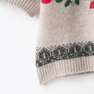 Detailed view of floral embroidery and geometric jacquard on oatmeal knitted short sleeve