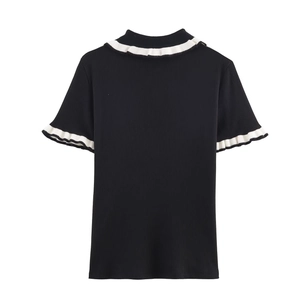 Detail shot of black ribbed knit top showing delicate white ruffled collar and cuffs