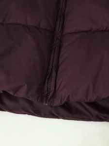 Detail of dark purple quilted puffer jacket with horizontal stitching and durable zipper