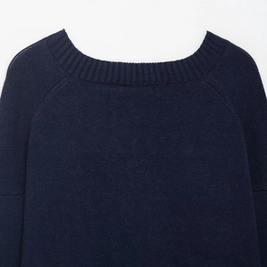 Detail view of ribbed crew neck and raglan sleeve stitching on navy blue knit sweater