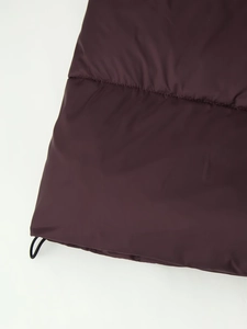 Detailed close-up of dark purple quilted jacket with elastic drawstring hem and texture