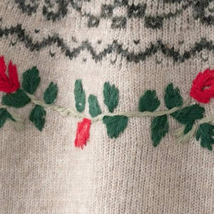 Detail view of oatmeal knit sweater with Fair Isle pattern and floral rose embroidery